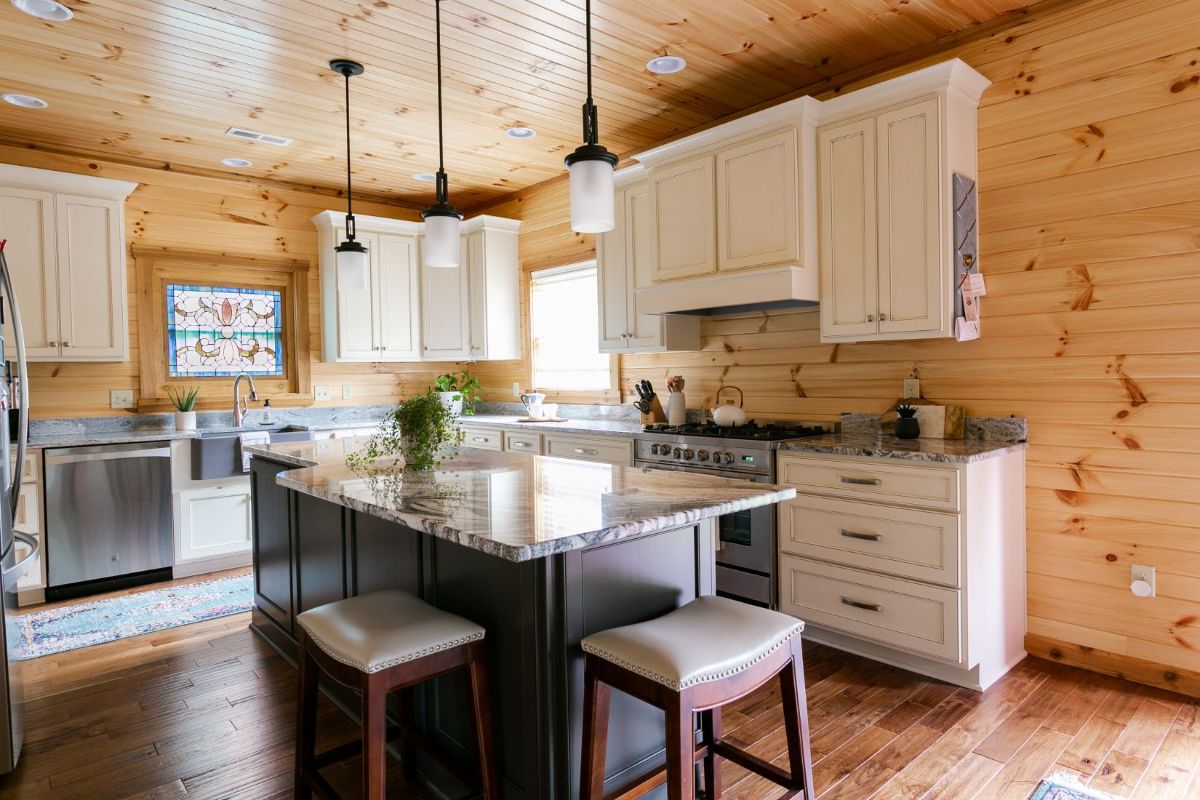 white kitchen cabinets with stainless steel apliances and dark wood island with stools around it