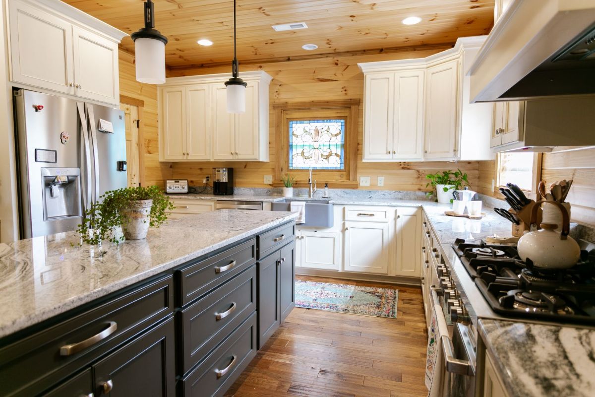 white fixtures dangling above a white counter over dark wood island next to white cabinets in kitchen