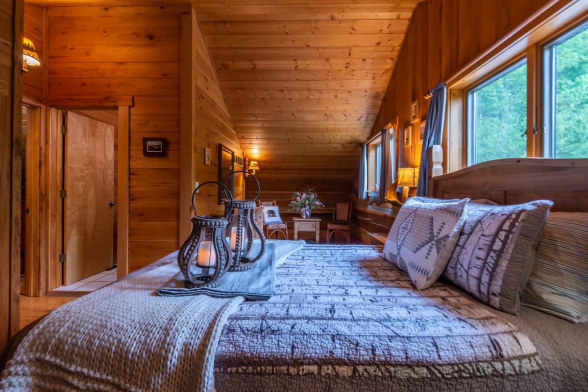 view across bed in log cabin with open door on far left