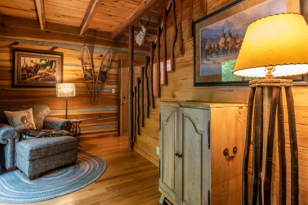 storage hutch below picture against wall by stairs in log cabin living area