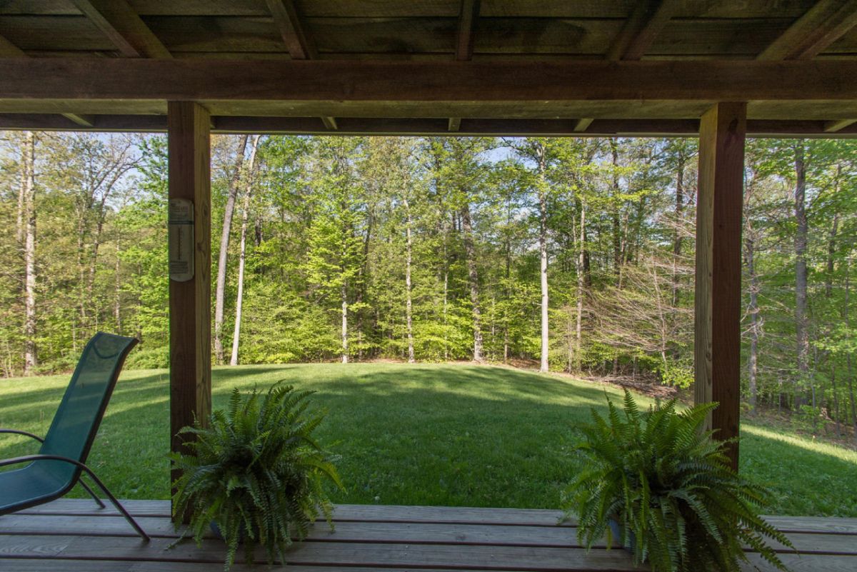 view off front porch of log cabin with ferns on deck on each side of column