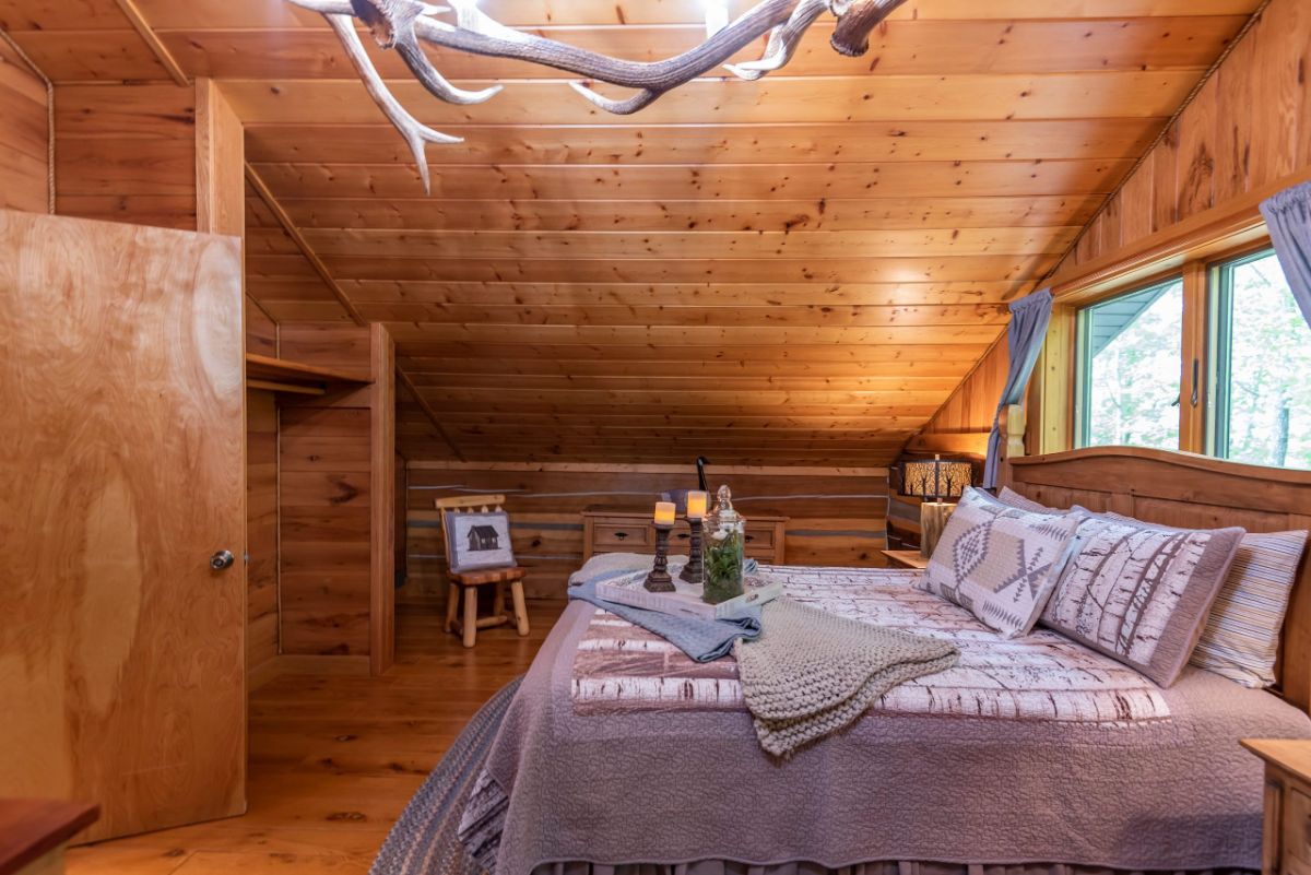 antler chandelier above bed in log cabin loft bedroom