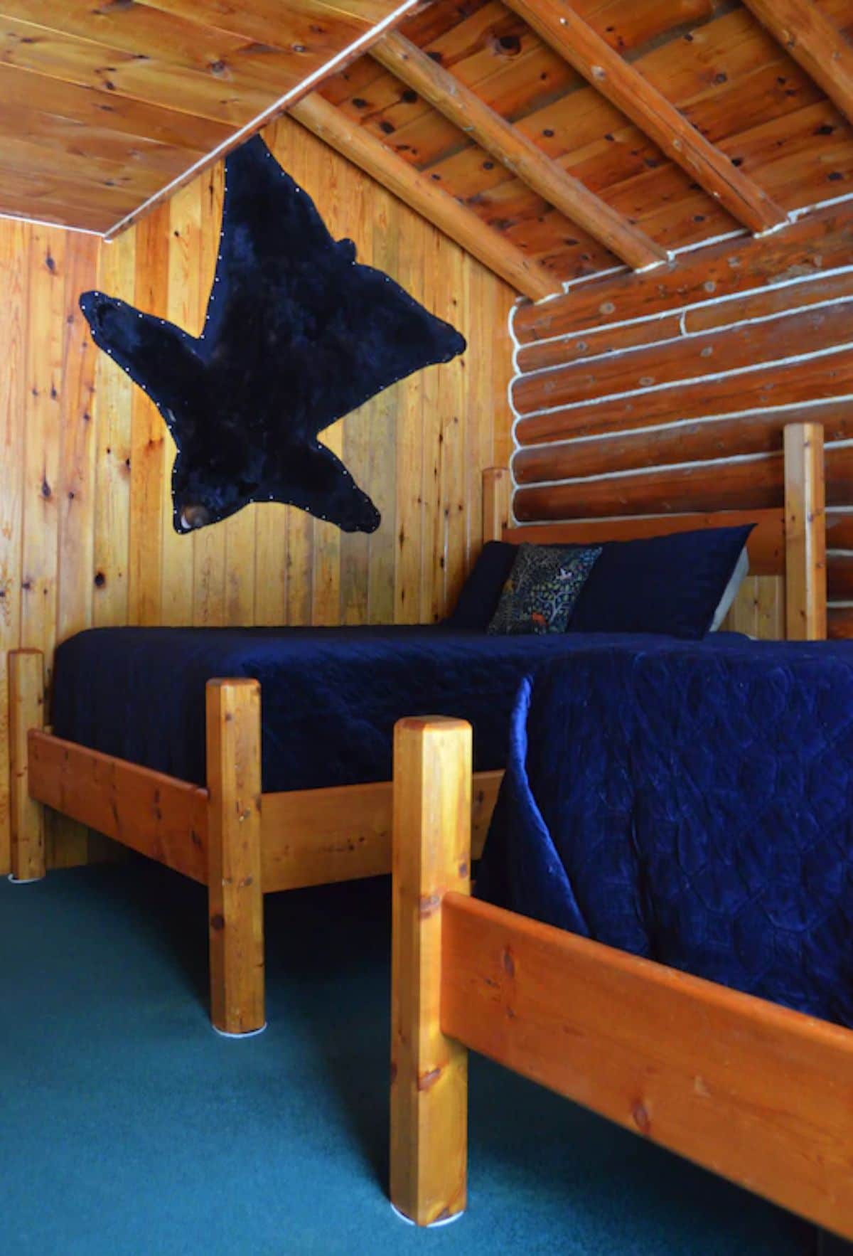 two beds with blue bedding and blue bear rug on wall