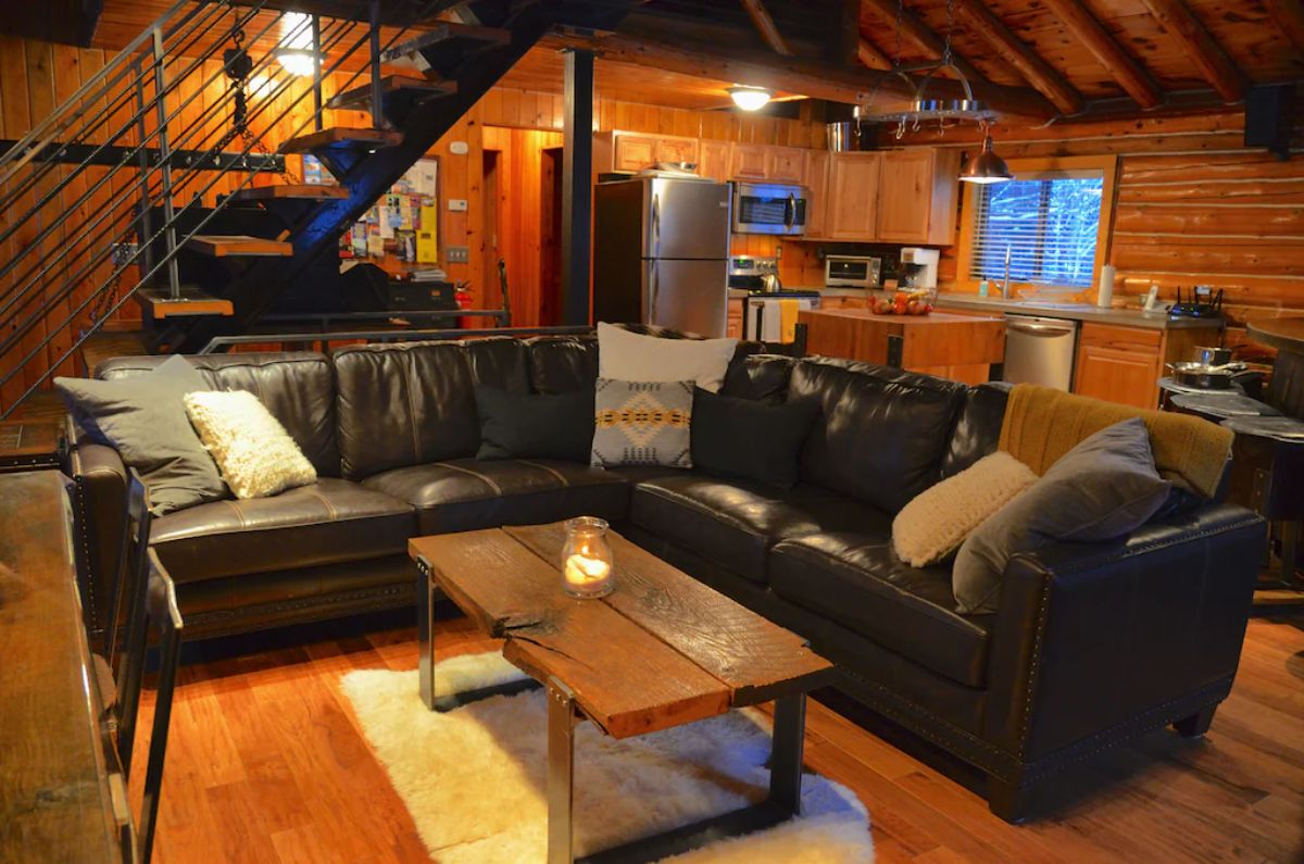 two leather sofas against each other in living area with kitchen in background