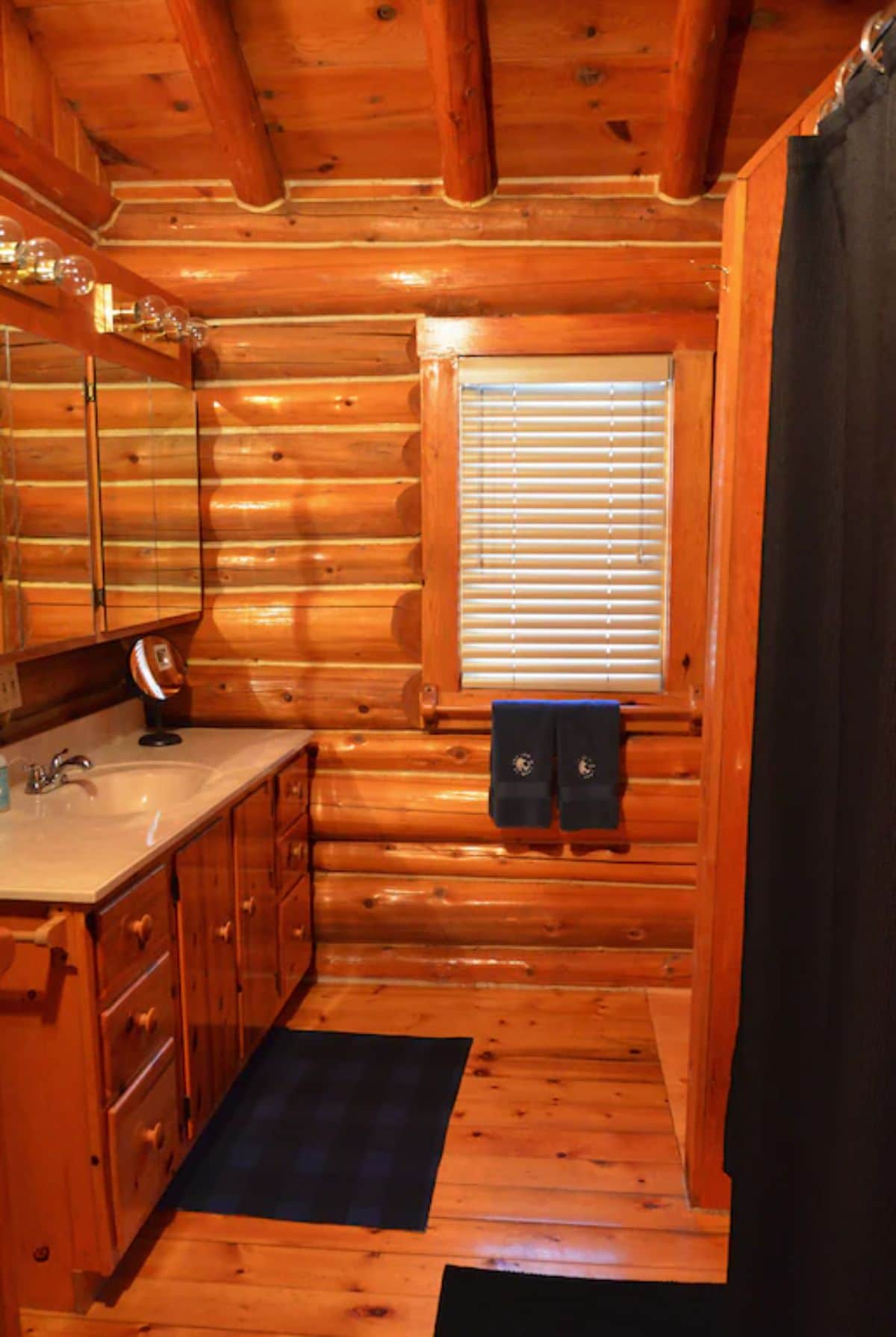 log cabin bathroom with log walls and vanity with white counter