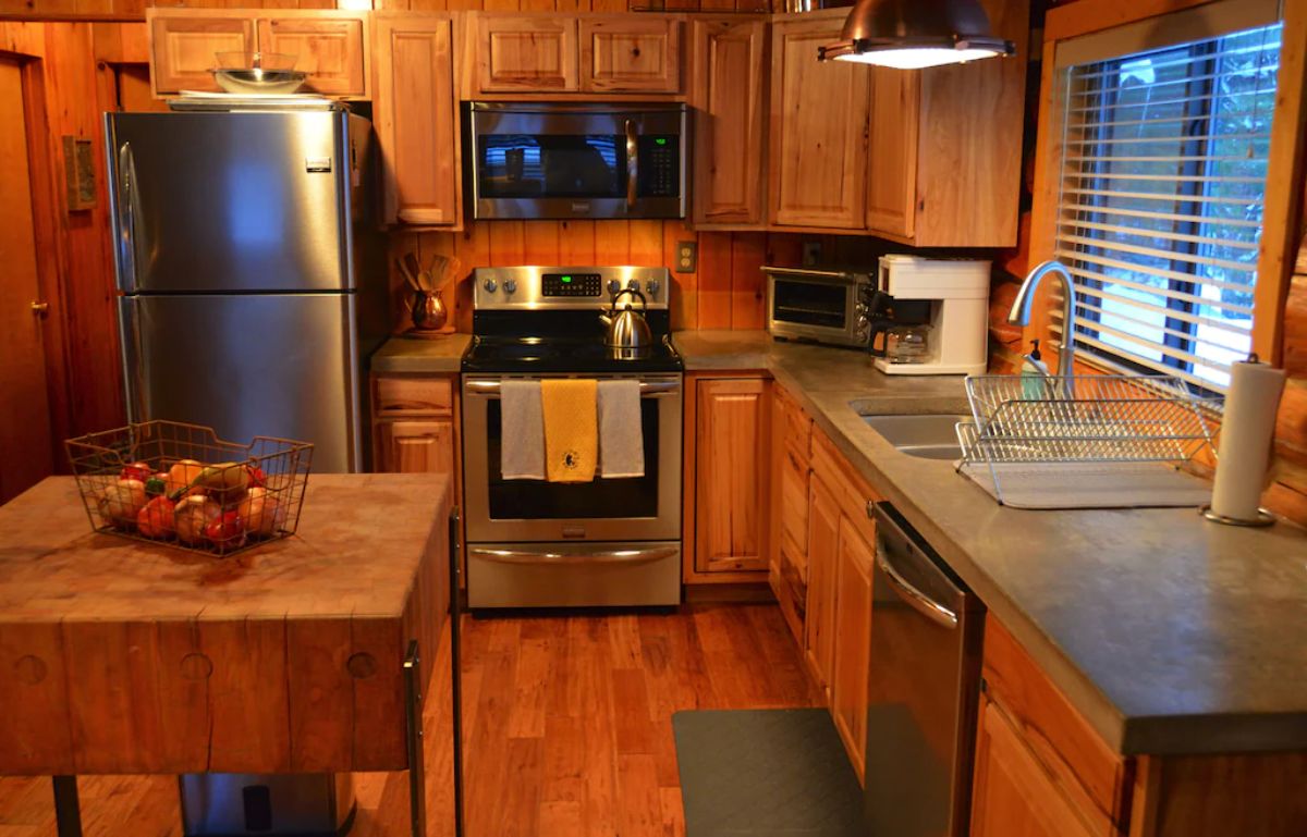 stainless steel stove against far wall of kitchen with wood cabinets