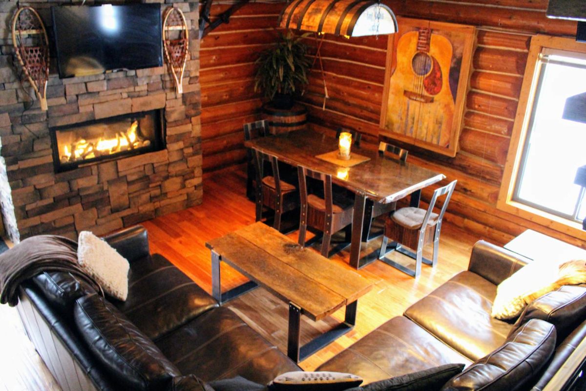 view from loft into dining space with wood table against wall on right with fireplace on left