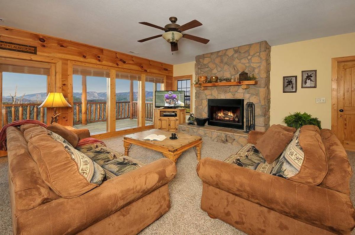 stone fireplace against wall of basement with brown sofas in foreground