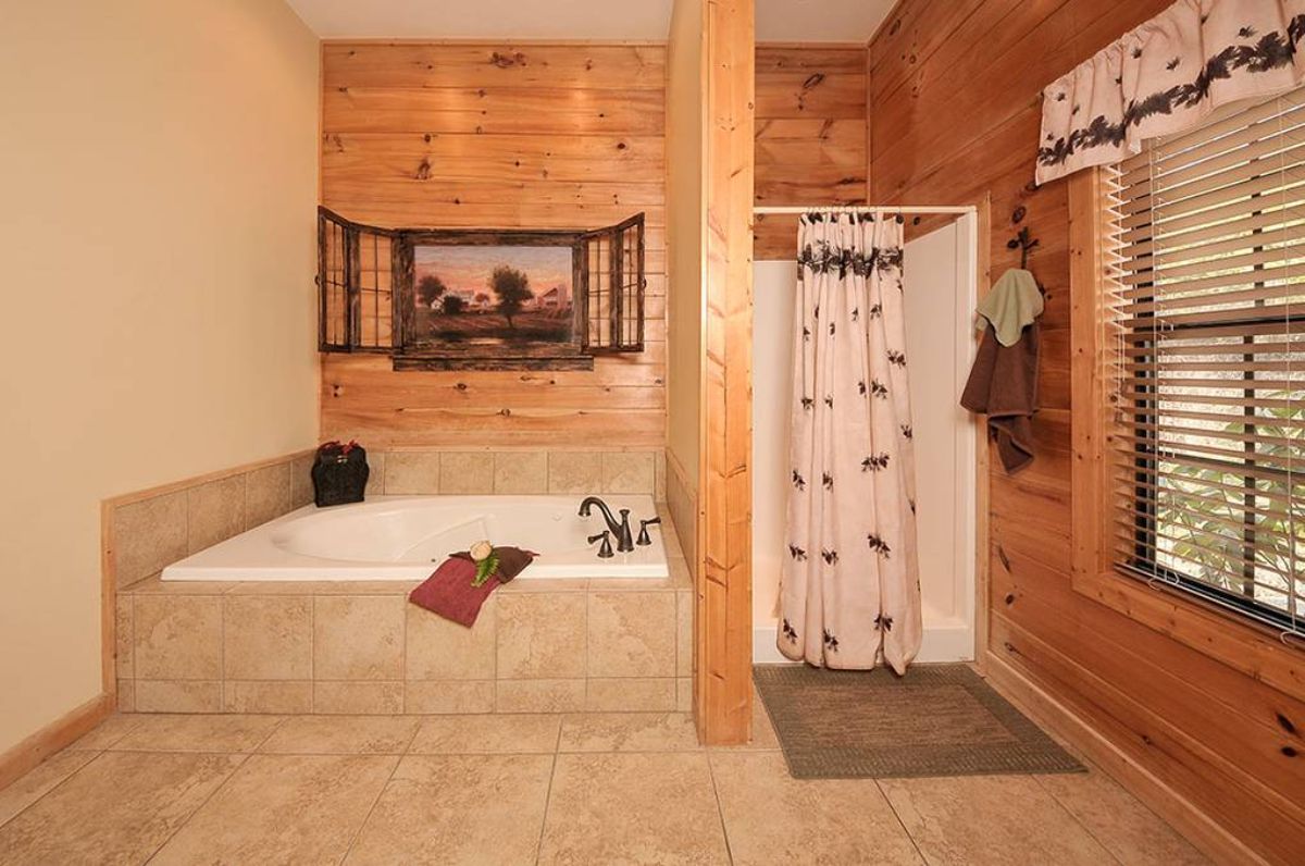 soaking tub surrounded by tile in bathroom next to wall of white shower stall
