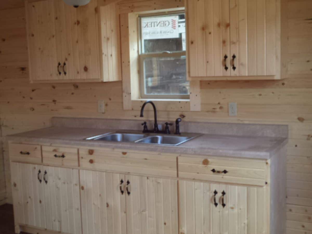 kitchen against back of log cabin with light wood cabinets and gray countertop