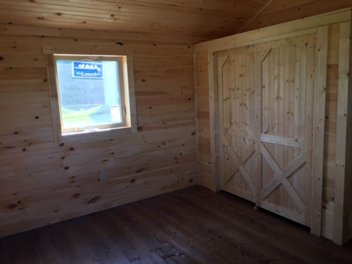 barn door against wall of log cabin with window on side wall