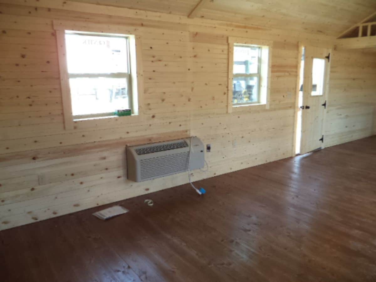 long wall in log cabin with two windows and door