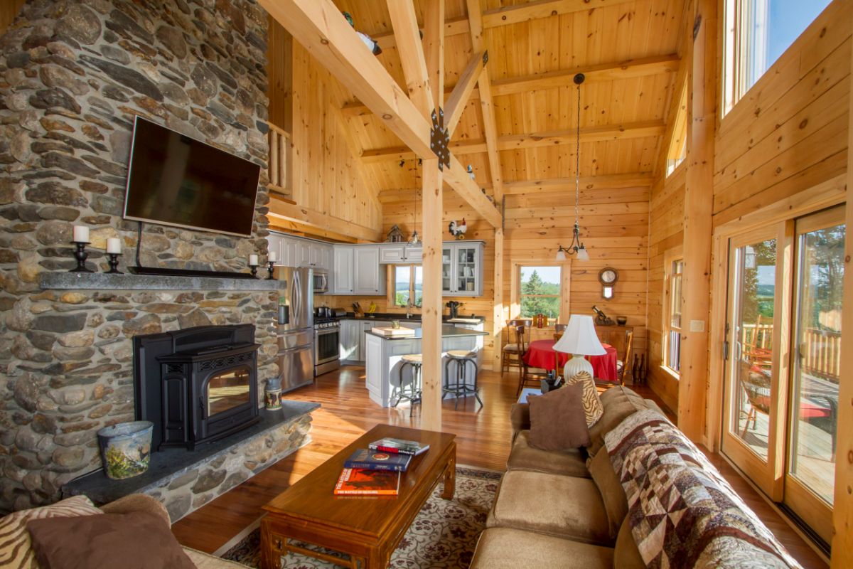 wall of windows on right and fireplace on left in log cabin