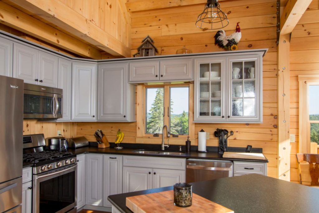 gray cabinets with black and steel appliances in kitchen of log cabin