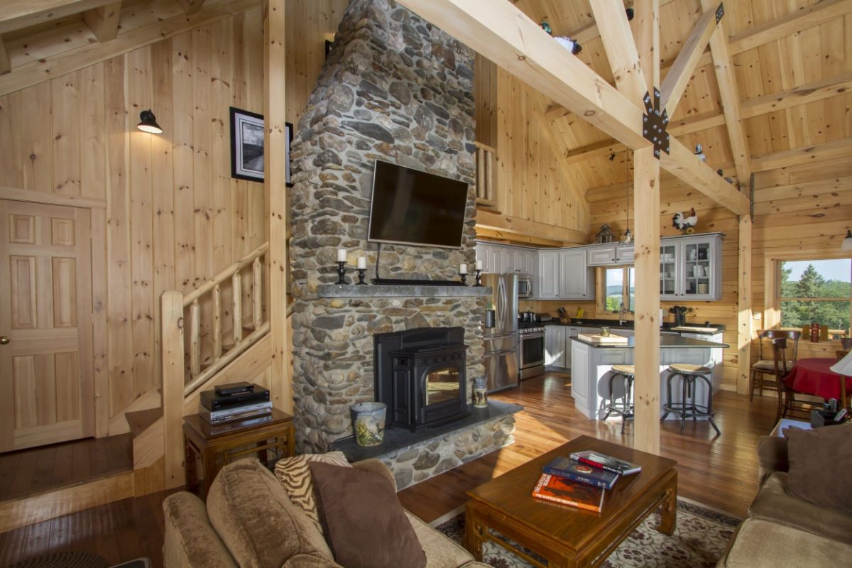 stone fireplace against wall with stairs in background to loft in log cabin