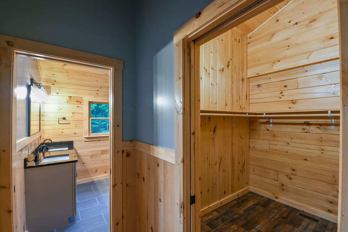 light blue half wall in log cabin bedroom with open walkin closet on right and bathroom to left