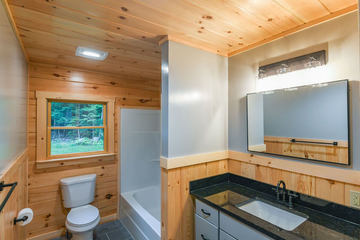 bathtub shower combination beside white toilet with black counter above blue cabinets in bathroom