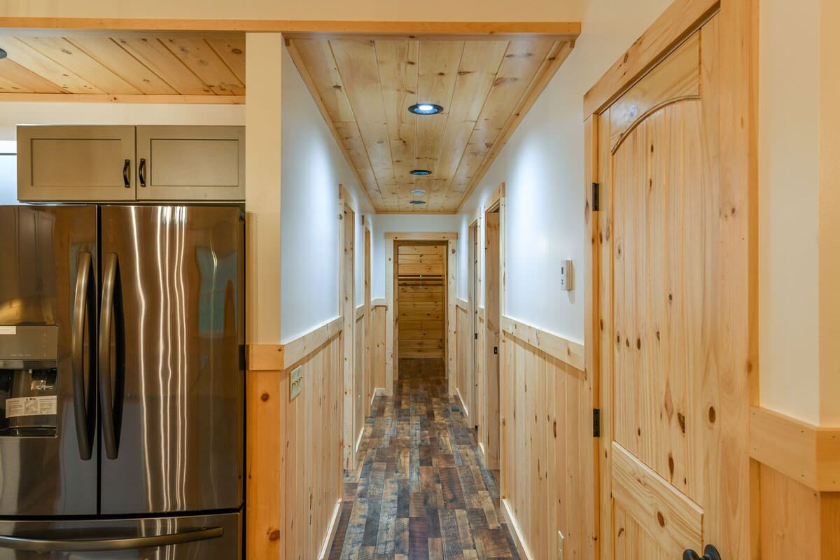 hallway with light wood trim on doors next to stainless steel refrigerator