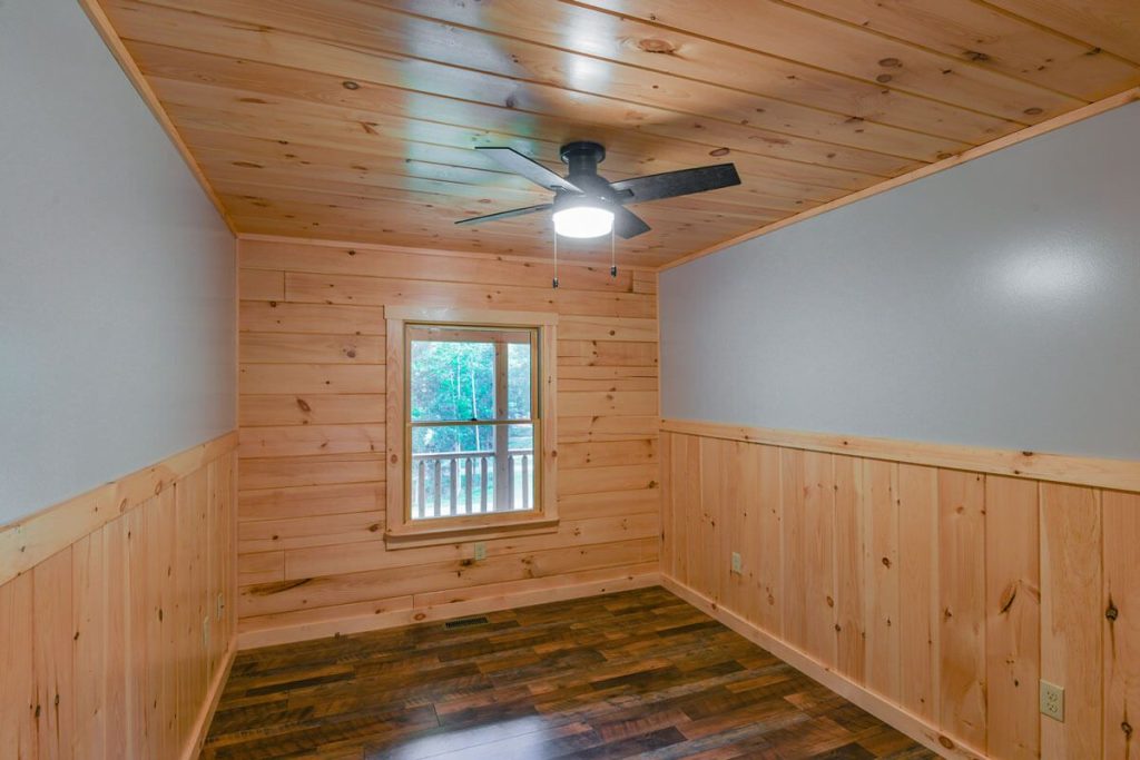 bedroom with wood ceiling and wainstcotting and ceiling fan in center of the room