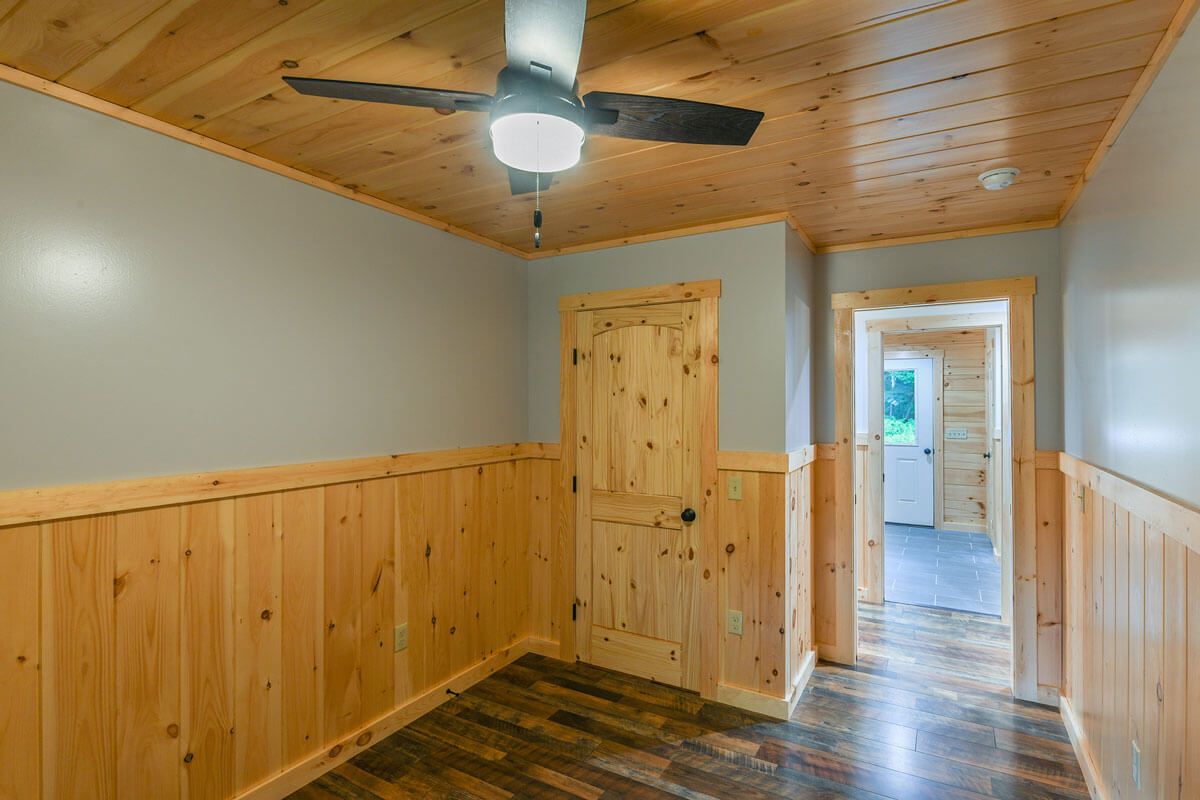 open door of bedroom with light wood half walls and door on closet at the edge of the room