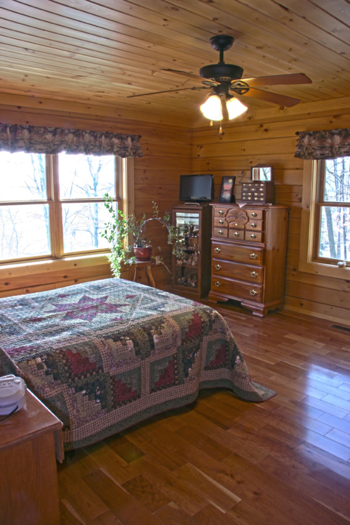quilt on bed in log cabin bedroom with windows on left