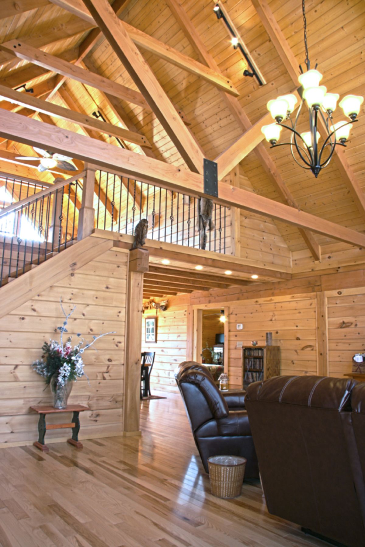loft above living room in log cabin with black leather sofa in foreground