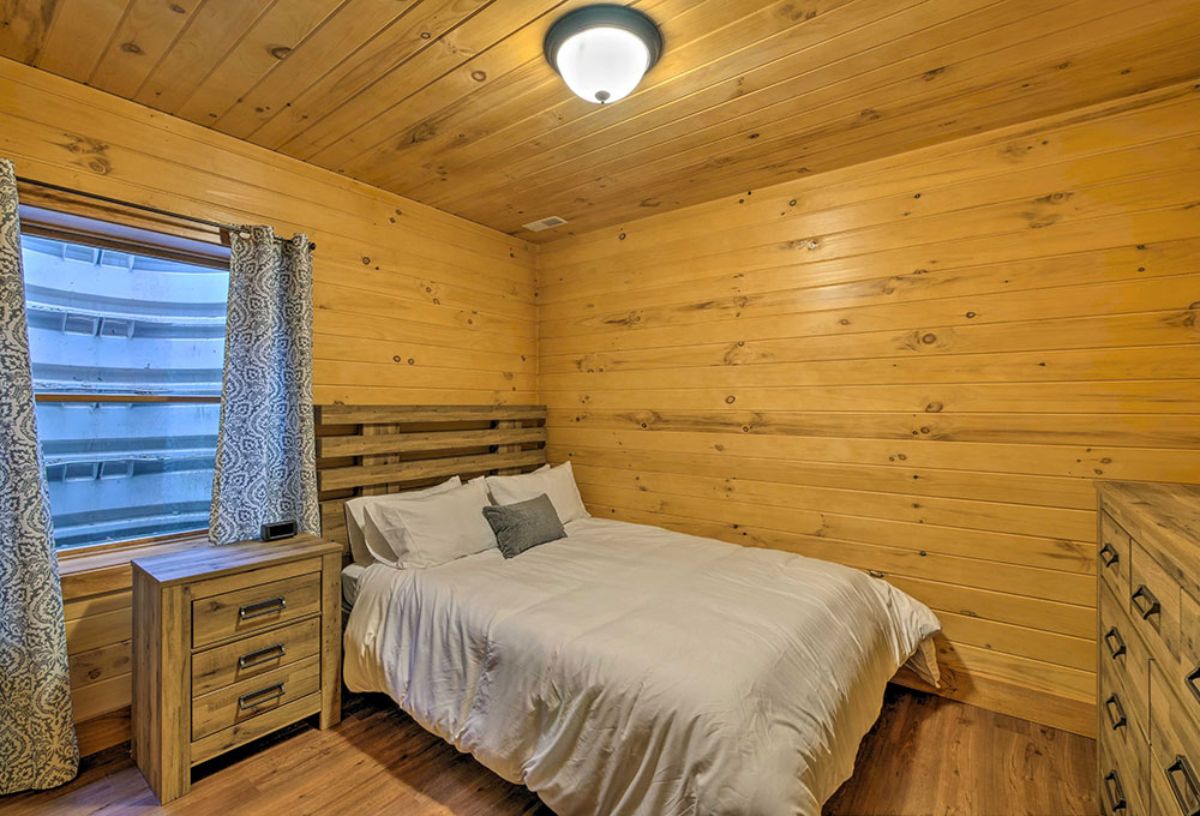 bed against log cabin wall with white bedding