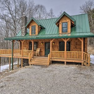 log cabin with porch over side of hill and green roof
