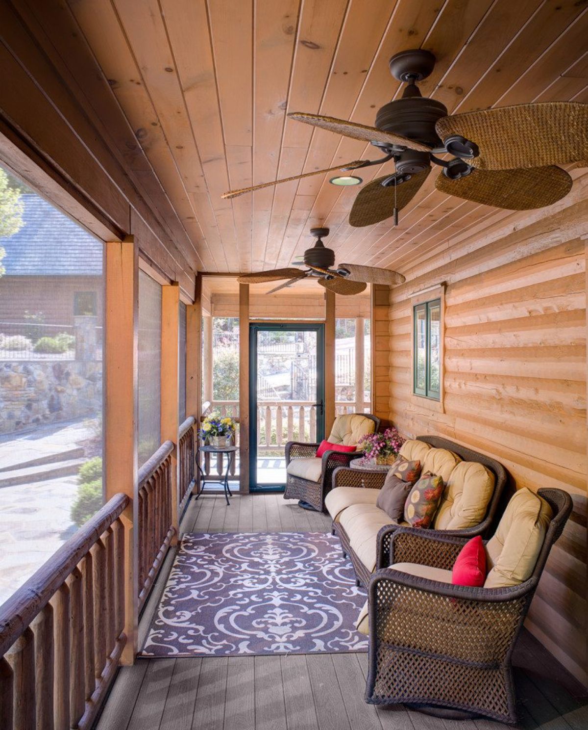 wicker chairs against wall in covered screen porch off log cabin