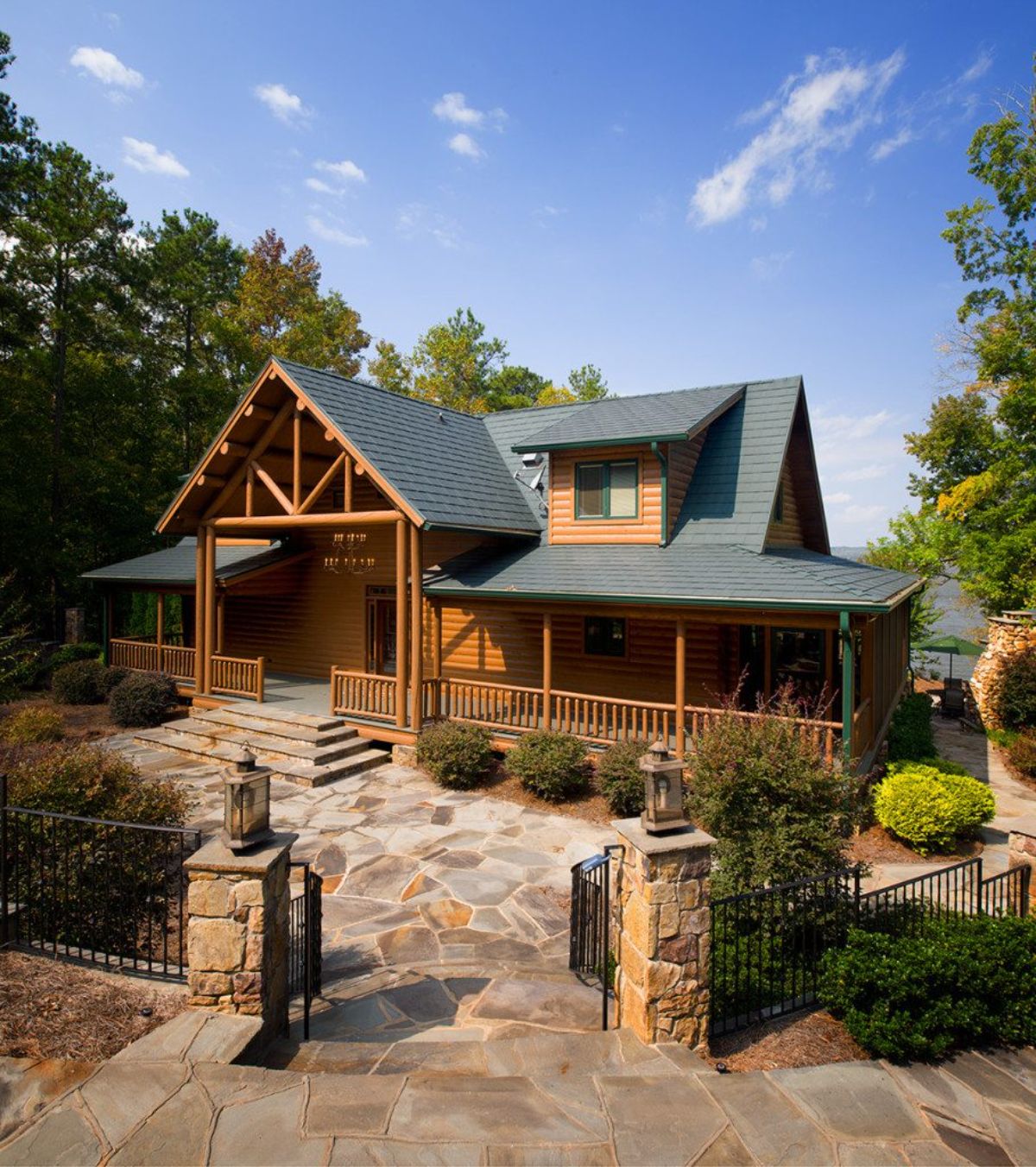 log cabin with covered porch and green roof behind rock landscaping