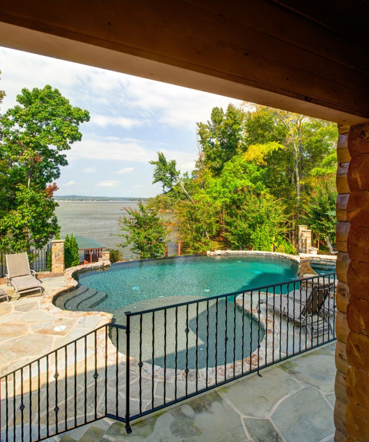 view off deck with wire fence showcasing pool behind log cabin