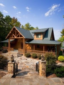 log cabin with covered porch and green roof behind rock landscaping