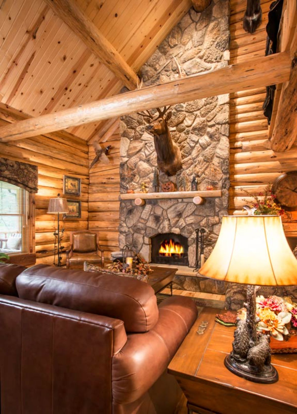 mounted deer head on top of fireplace in living room of log cabin
