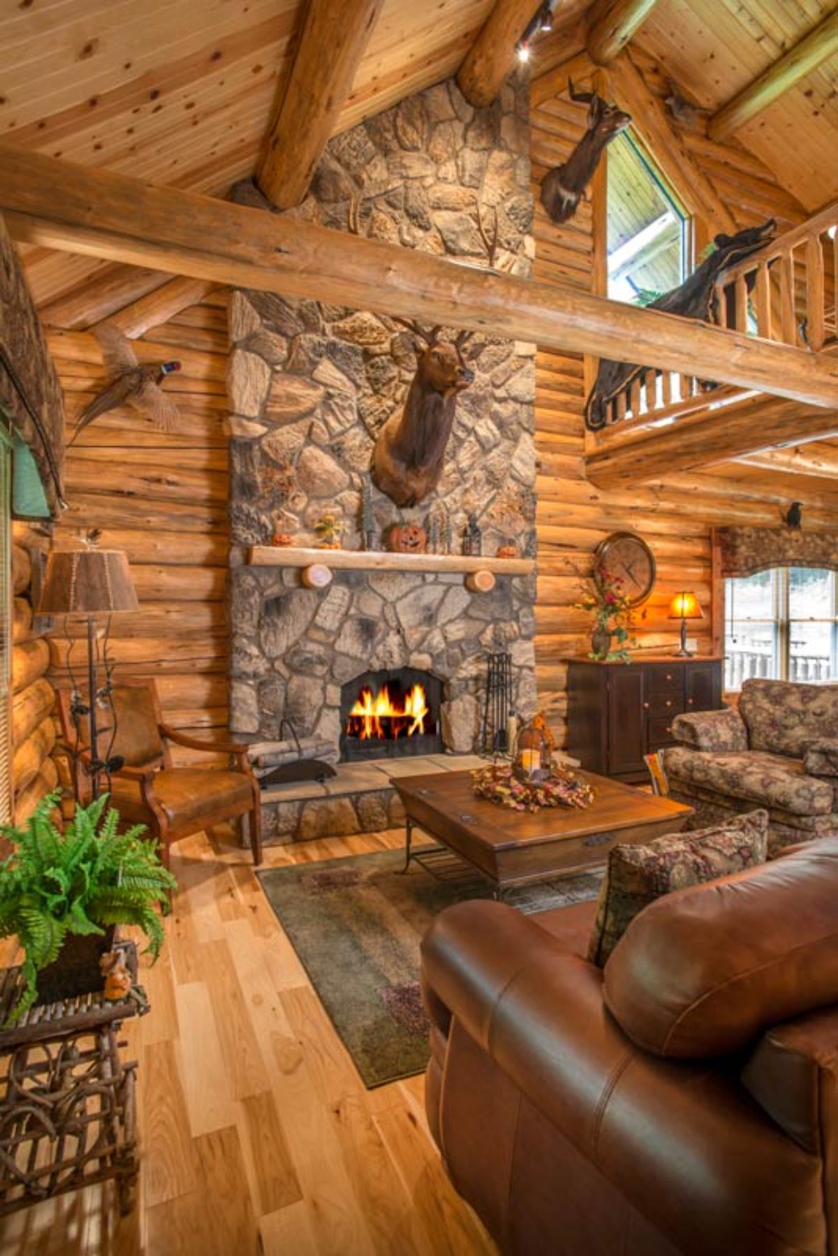 stone fireplace in log cabin with brown leather sofa in foreground