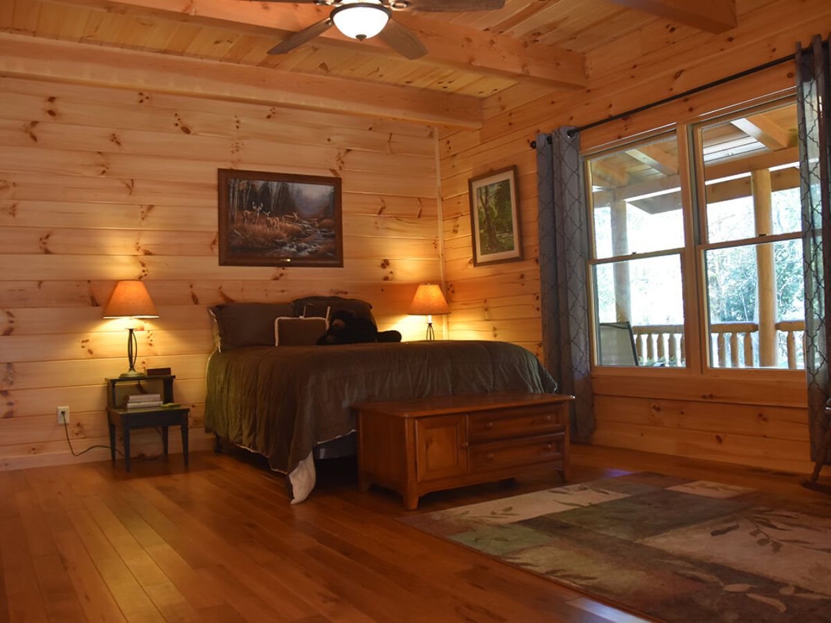 wood bed against wall with wall of windows on right side of room