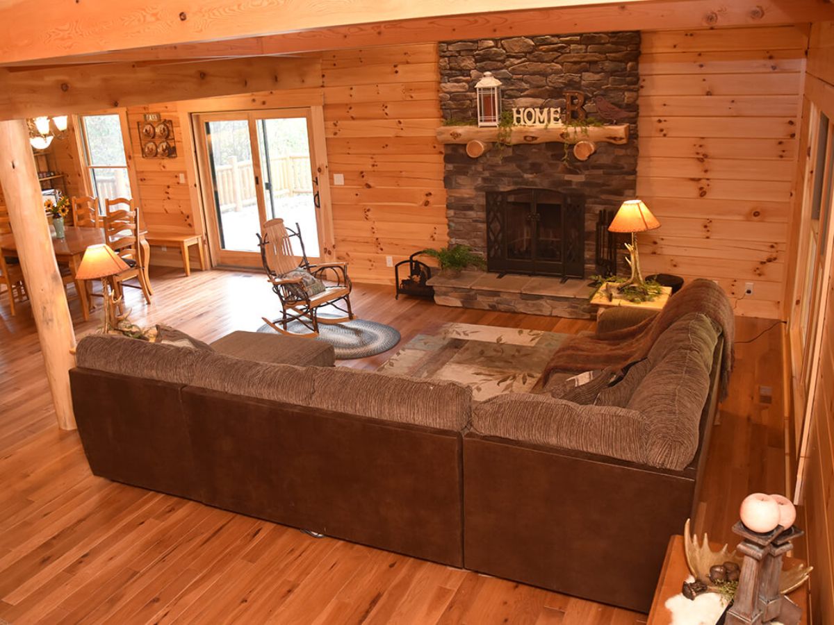 brown leather sofa in front of stone fireplace in log cabin