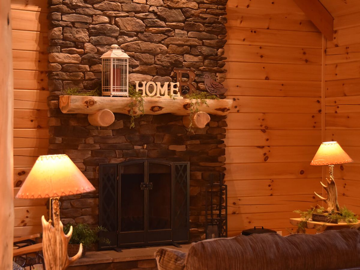 stone fireplace with log mantle against wall of log cabin