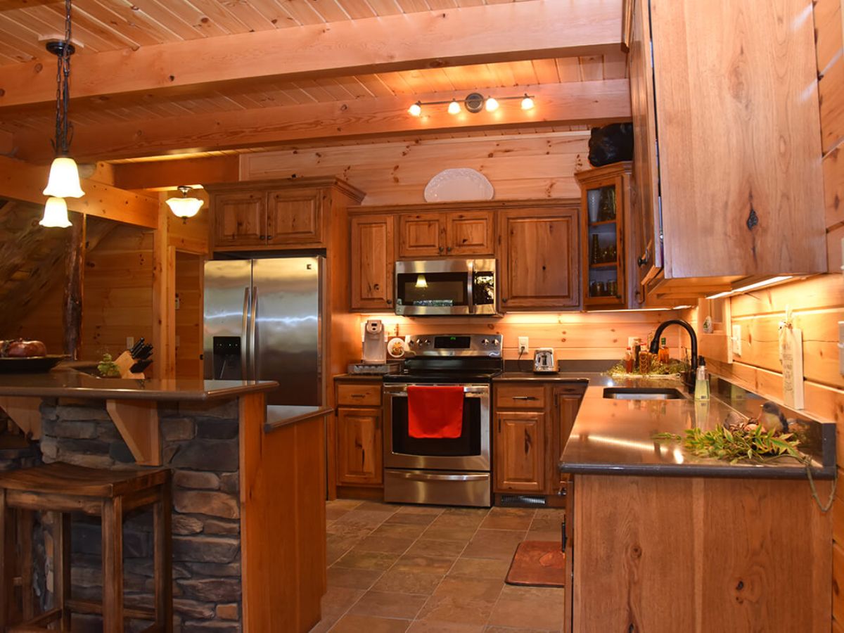 wood cabinets with granite countertops in log cabin kitchen with stainless steel stove