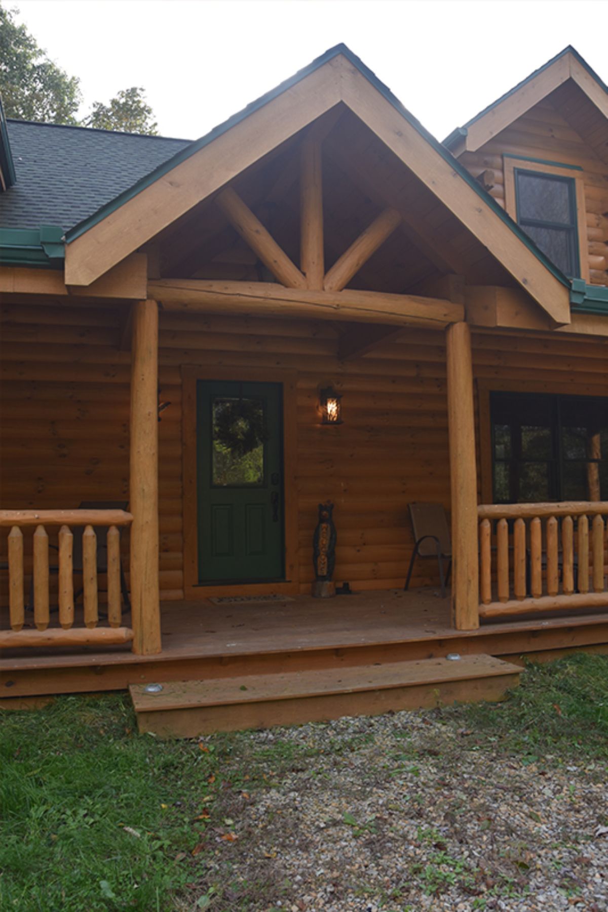 front door on log cabin with covered porch