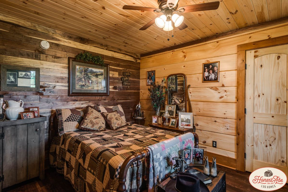 bed against log cabin wall with ceiling fan above