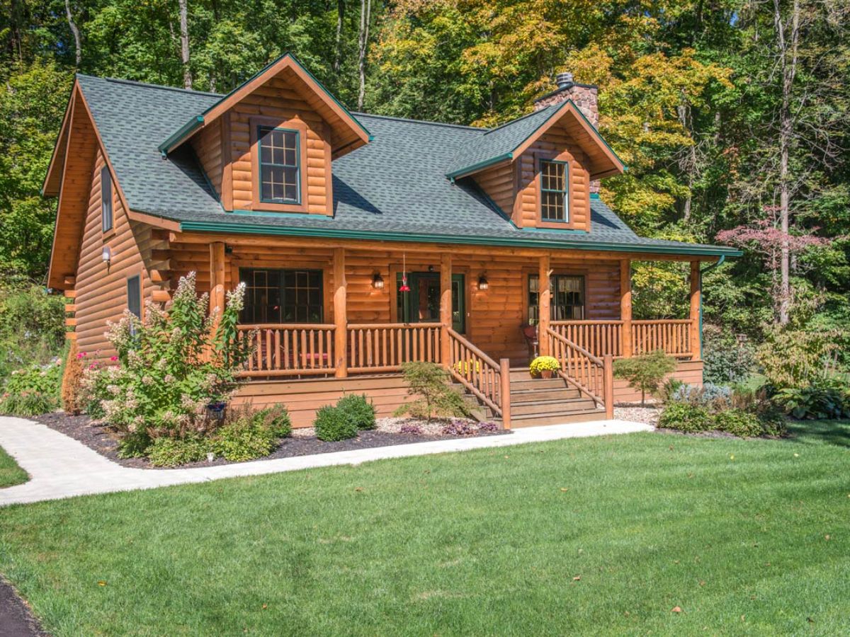 front porch on log cabin with green roof and wood railing