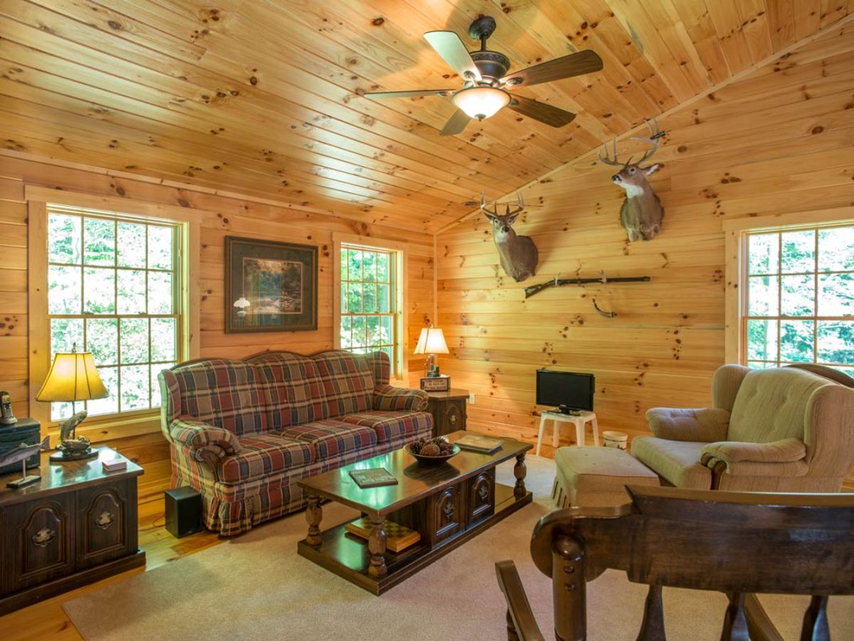 brown cloth sofa under windows against left wall with light colored chair on right