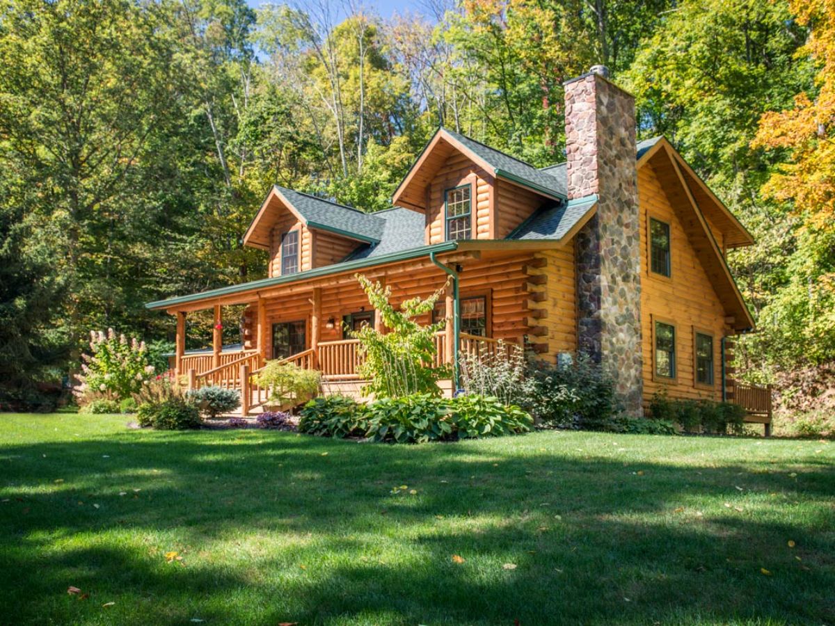 side of log cabin showing rock chimney on right side