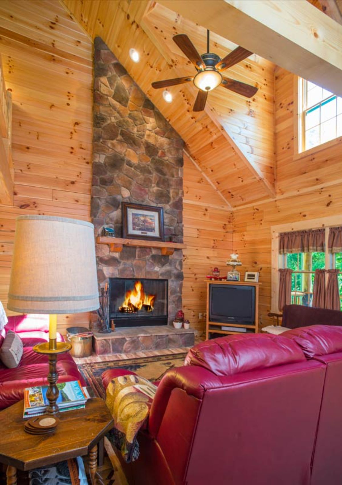 slanted roof in living room with stone fireplace and red leather sofas