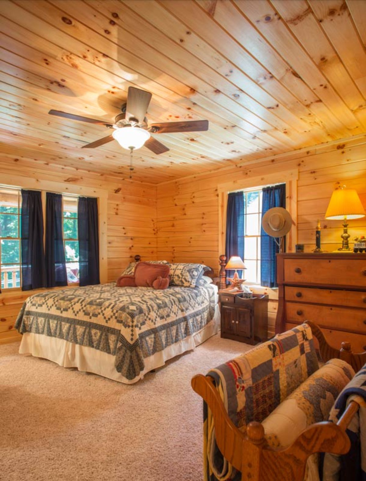 bed against wall in log cabin bedroom with green curtains