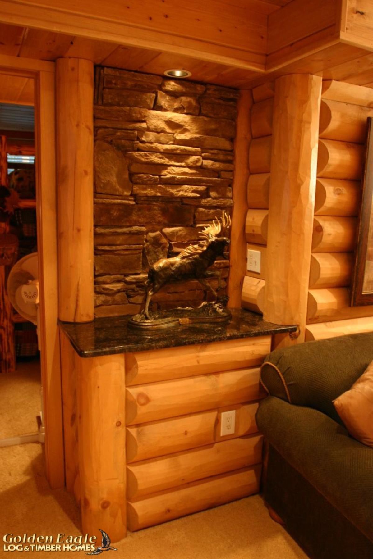 stone and log nook next to green sofa in log cabin basement