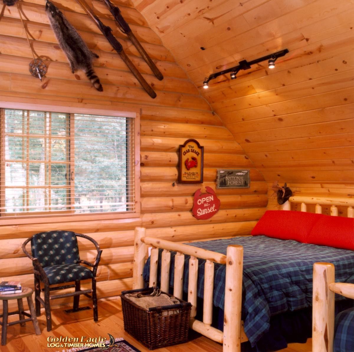 blue and red bedding on bed in log cabin
