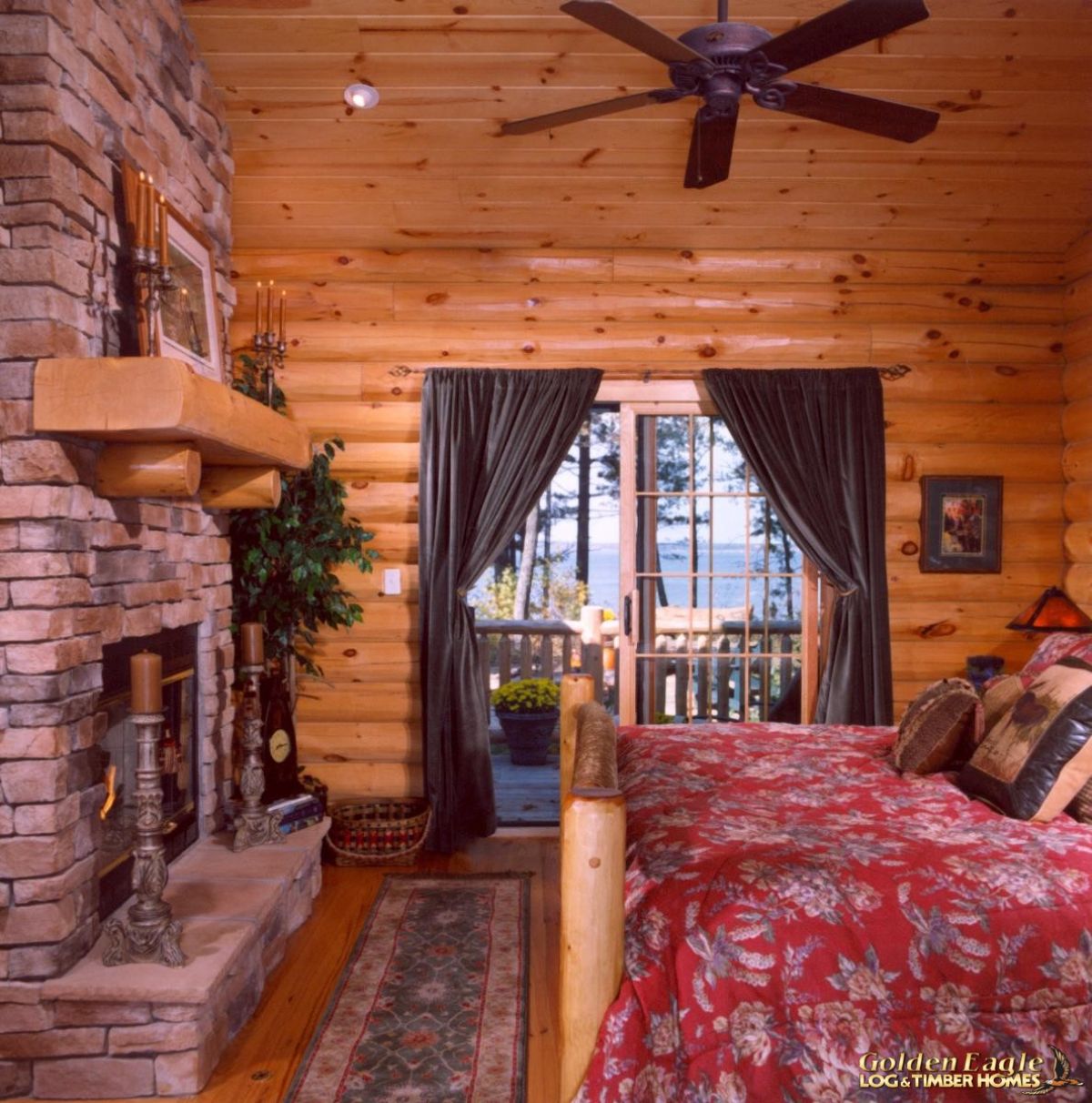 red bedding on wood bed with fireplace across from it and french doors in background