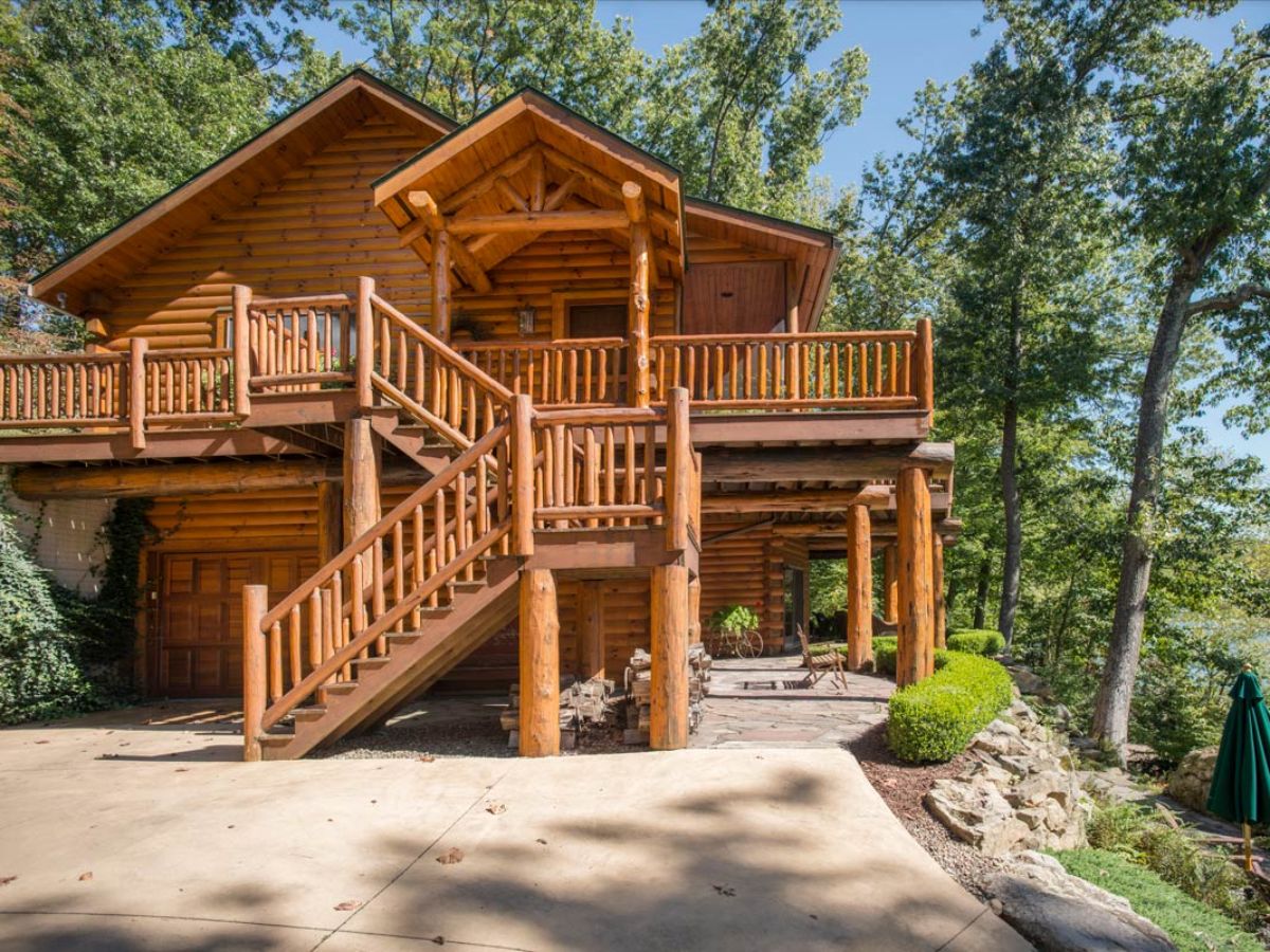 side of log cabin driveway with stairs to upper deck levels