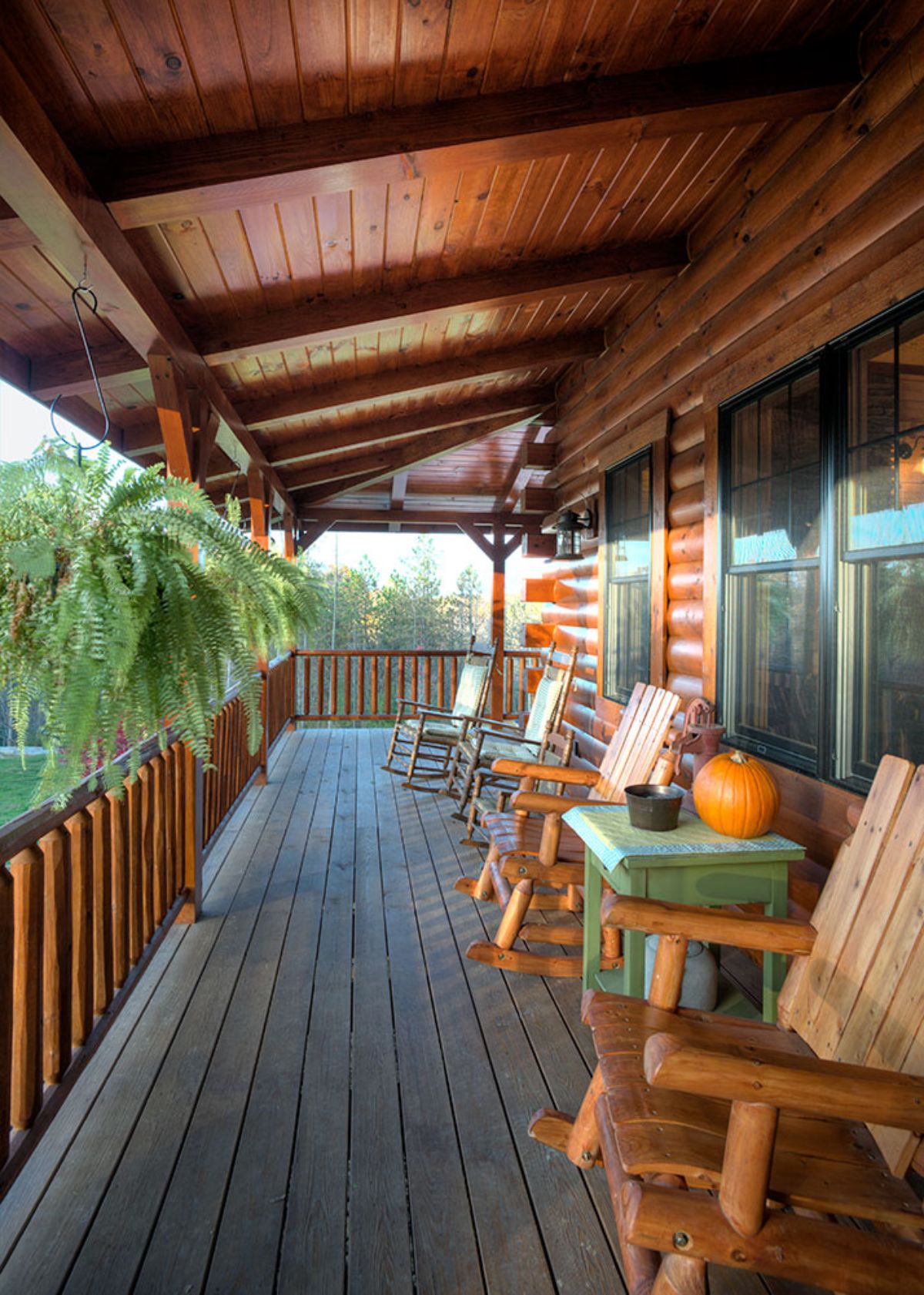 front porch on log cabin with rocking chairs and green table